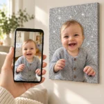 Poza unui bebeluș pe telefon și tabloul pe glitter argintiu, pe perete